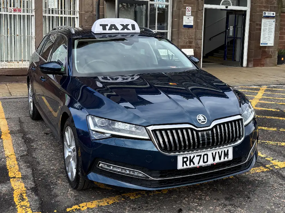 Dark blue taxi sitting outside of a railway station